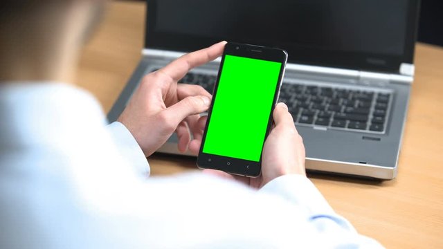 Businessman in office scrolling mobile green screen cell phone pre-keyed gesture