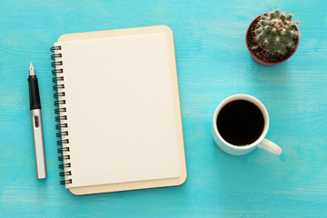 Open notebook with empty pages and other office supplies over blue office desk table. Top view