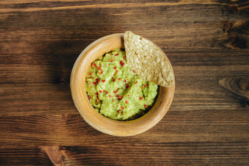 bowl of mexican guacamole with nachos on a table
