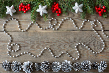 Christmas card concept with fir tree branches, rowan berries, silver cones, bead chain and silver...