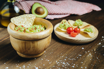 guacamole with nachos and avocado on wooden table