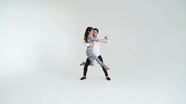 Concept of love, relationships and social dancing. Young beautiful couple dancing sensual dance on a white background