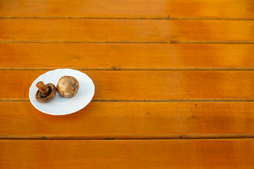 Grilled champignons on a white plate on a wooden table. Healthy food. Close up.