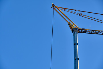 Yellow crane against the blue sky with moon in the evening light