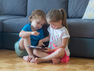 Brother and sister play games on the tablet, watch cartoons 