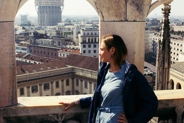 A young attractive Caucasian woman examines the city of Milan from the roof of the Duomo, excursions to Europe, a tourist concept.