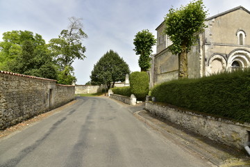 Fototapeta na wymiar Route de campagne entre les murs d'enceinte du château et l'église de Vendoire au Périgord Vert