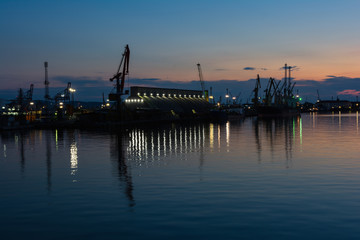 Fototapeta premium Burrgas Sea Port at night. Silhouettes of cranes and reflections in the water