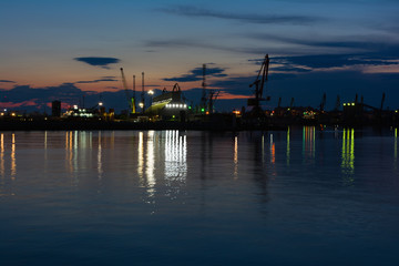 Fototapeta na wymiar Burrgas Sea Port at night. Silhouettes of cranes and reflections in the water