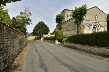 Fototapeta na wymiar Route de campagne entre les murs d'enceinte du château et l'église de Vendoire au Périgord Vert