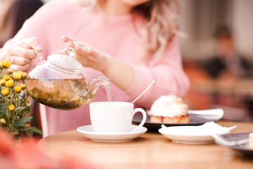 Girl holding pot with green tea on cafe outdoors closeup. Good morning. Breakfast.