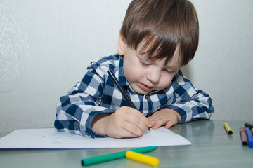 The boy draws felt-tip pens on paper. Drawing. Little boy. Children's drawing. Developmental activities.