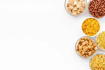 Various corn cereals in bowls on white background top view copyspace