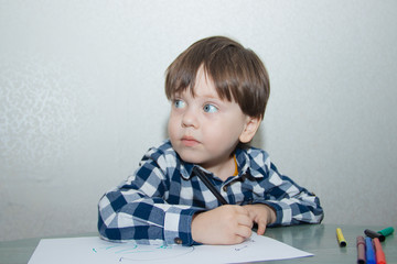 Naklejka premium The boy draws felt-tip pens on paper. Drawing. Little boy. Children's drawing. Developmental activities.