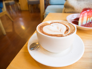 Hot latte art coffee in white cup on wood table