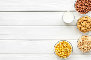 cereals, oatflakes and cornflakes with milk for healthy breakfast on white wooden background top view mock up