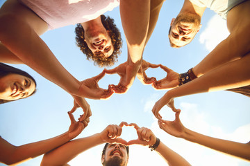 Hands of group people in the shape of a heart against the sky.