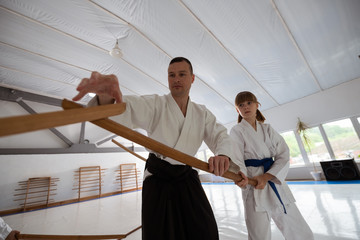 Trainer helping girl to use jo while practicing martial arts