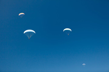 Many paragliders in the blue sky. 