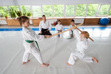 Boy and girl having aikido fight using jo