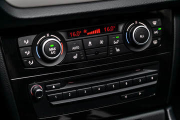Сlose-up of the car  black interior:  dashboard with temperature, clock, adjustment of the blower, air conditioner and other buttons.