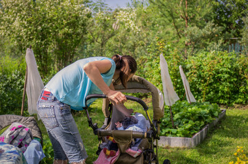 Naklejka na ściany i meble Young mother with a small child in a stroller resting in nature