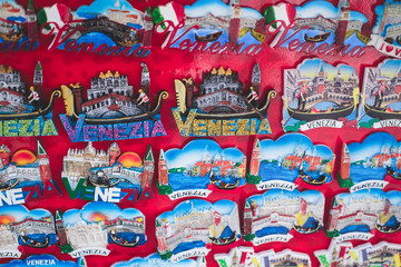 View of traditional tourist souvenirs and gifts from Venice, Italy and with toys, masquerade venetian masks, fridge magnets with text "Venice" and key ring keychain, in local vendor souvenir shop
