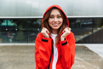 Beautiful excited emotional young happy pretty woman in raincoat posing outdoors.