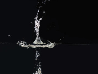 Drop of water making splash on surface, isolated on black background, close up view. Water bubbles. Ready to use blending mode to screen or add