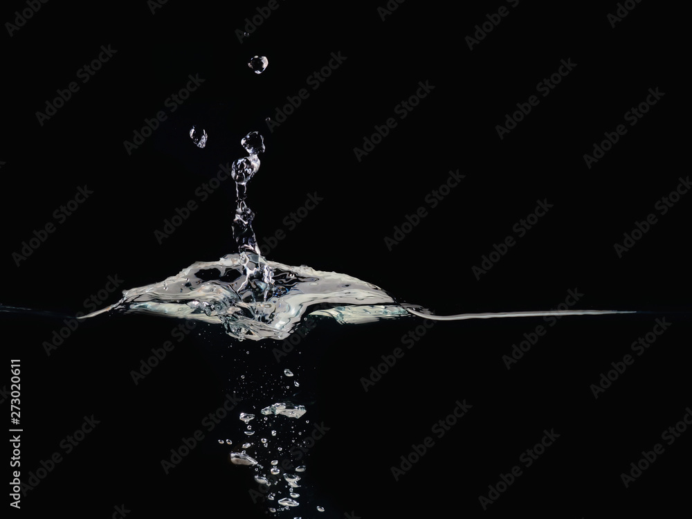 Poster drop of water splashes on surface making bubbles and rippling, isolated on black background, close u