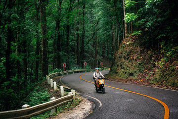 Man with backpack sits on road through green Bilar Man-Made Forest, Bohol, Philippines