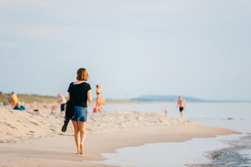 Woman walking along beach near the sea in summer.