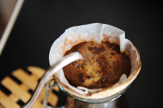 Unusual creative coconut shell pourover alternative coffee brewing drip water with gooseneck kettle close up