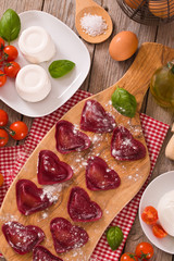 Fototapeta na wymiar Red heart ravioli with tomato, mozzarella and basil.