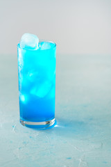 Blue Lagoon cocktail is a collins glass. Light blue background, real ice, high resolution