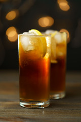 Rum and coke in a highball glass with a lemon wedge. Dark wooden table, festive lights, high resolution