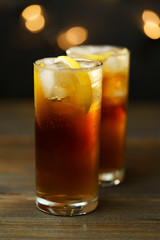 Rum and coke in a highball glass with a lemon wedge. Dark wooden table, festive lights, high resolution