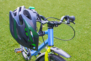 Cycling Helmet Closeup On Bicycle on the background of a green field