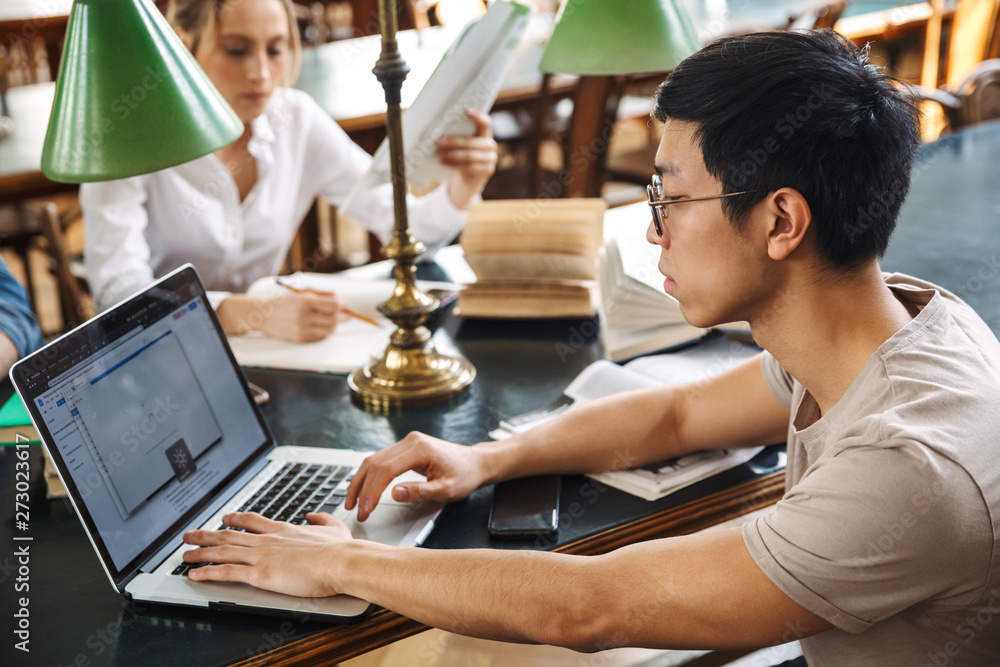 Wall mural smart pensive asian student studying with laptop