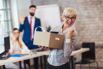 Elderly employee leaving office with box full of belongings. Time to retire