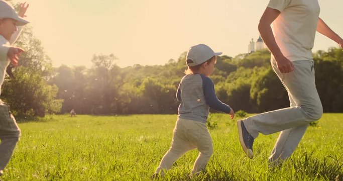Father with two sons playing football in the meadow