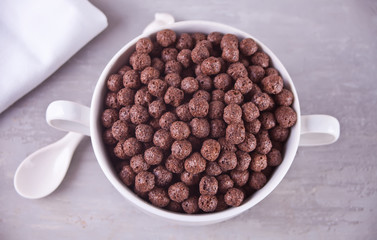 A bowl of dry chocolate balls cereal on the gray table for health breakfast