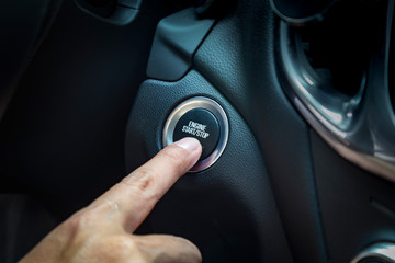 hand pushing a button to start car engine