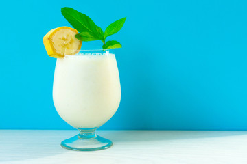 Banana milkshake with mint, on a bright blue and white background.Copy space