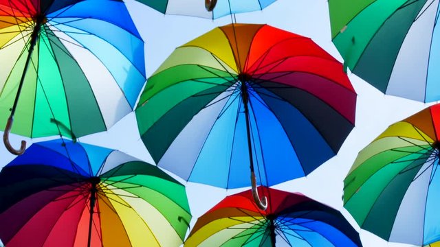 Street decoration with rainbow umbrellas hanging above street. Multi Colored art installation