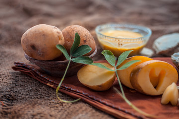 Face mask for the treatment of spot reduction consisting of potato juice and fuller's earth in a glass bowl, along with its entire raw ingredients.Horizontal shot.