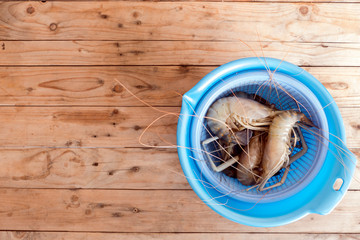 big prawns in the plastic basket on the wooden table