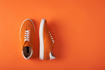 Top view of casual orange suede trainers on grey wooden planks