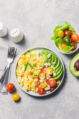 Scrambled eggs with cherry tomatoes , avocado feta cheese and olive oil. Top view, space for text.