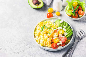 Scrambled eggs with cherry tomatoes , avocado feta cheese and olive oil. Top view, space for text.